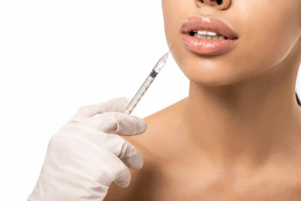 cropped shot of young woman getting beauty injection in lips isolated on white