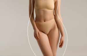 Close-up of fit woman’s torso in lingerie with contour lines, representing body shaping, liposuction, and fat grafting procedures for slimming and sculpting.