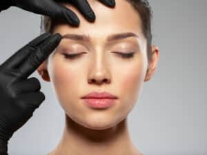 Plastic surgeon evaluating brow lift before treatment.