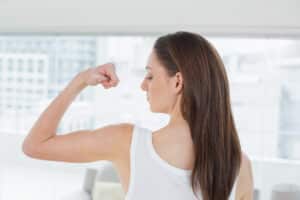 Woman flexing her arm after liposuction in Scottsdale
